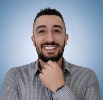 Leandro Guedes sorrindo em uma foto com o fundo azul